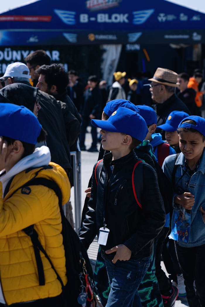 Children wearing blue caps attend Teknofest event outdoors in Istanbul.