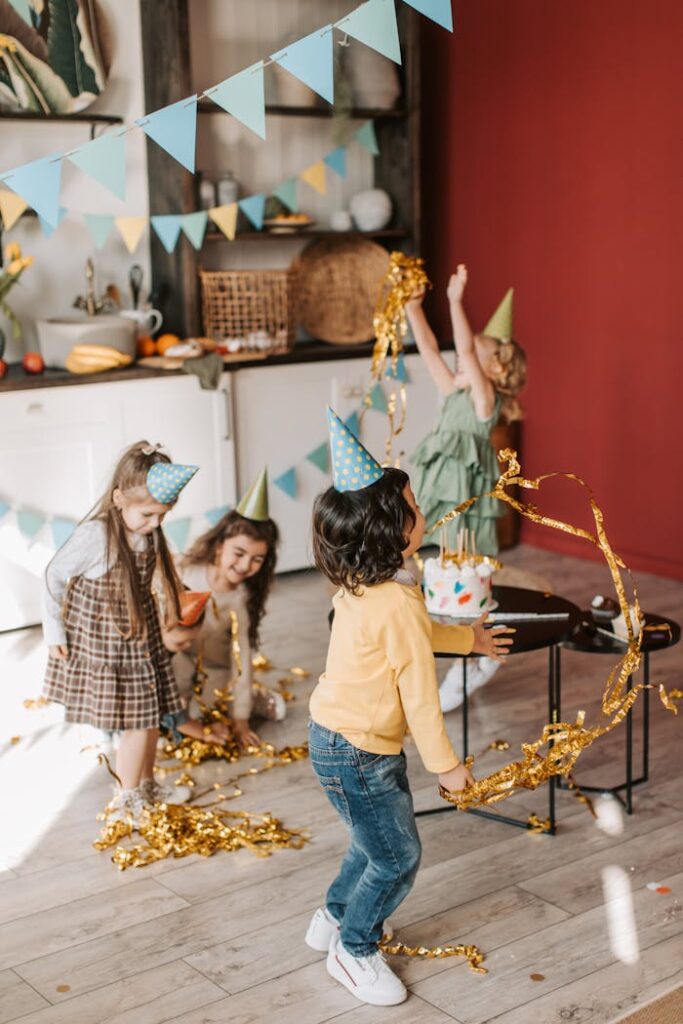 Kids in party hats delight in a festive birthday celebration with confetti.